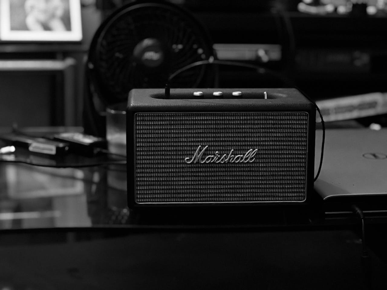 services-06 Black and white photograph of a Marshall Bluetooth speaker on a table.